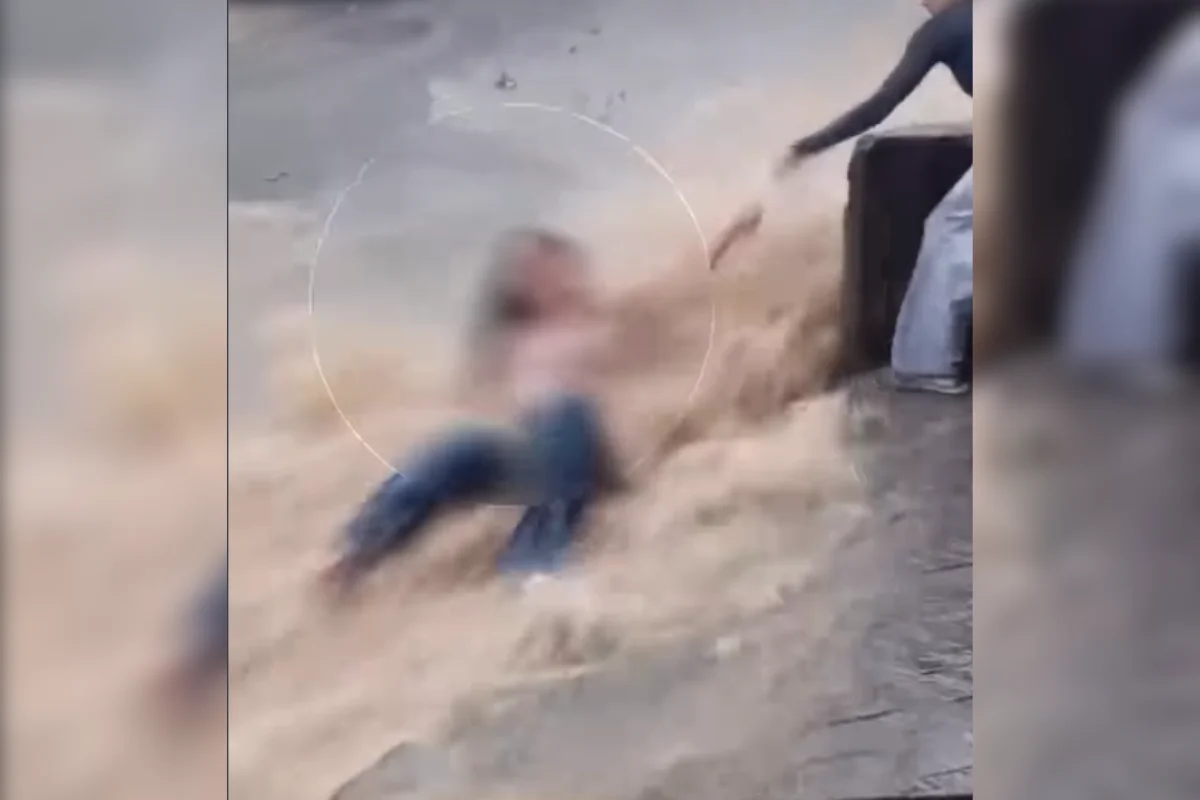 Imagem colorida de jovem sendo arrastada por enxurrada na rua - Metrópoles