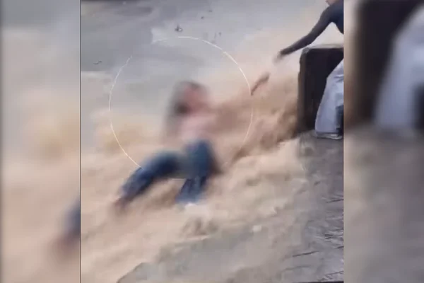 Jovem é resgatada após ser arrastada por enxurrada na rua e parar em poste